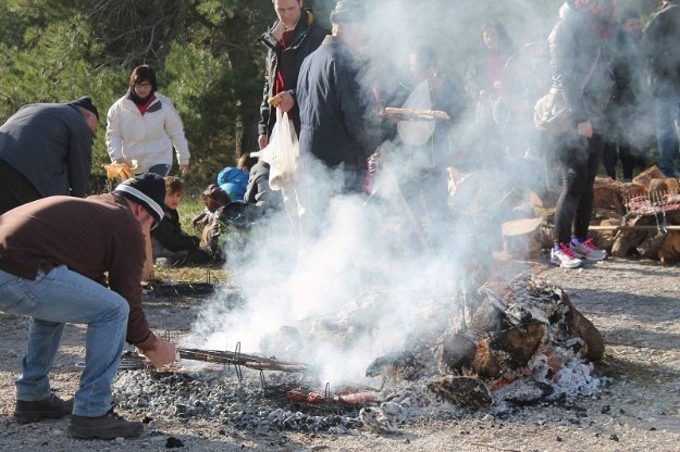 Grupo de peregrinos en un fuego asando salchichas y carne